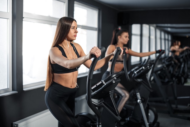 La mujer joven atractiva de los deportes se está ejercitando en el gimnasio. Haciendo entrenamiento cardiovascular en cinta. Corriendo en cinta. Foto de alta calidad