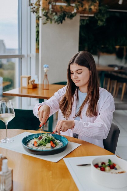 Foto mujer joven y atractiva disfruta de una comida sabrosa en un café o restaurante