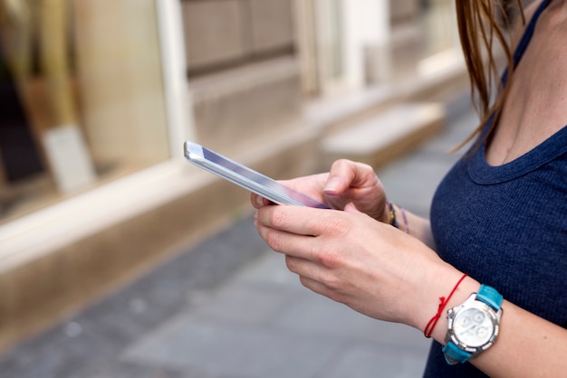 Mujer joven atractiva enviando mensajes de texto en la calle