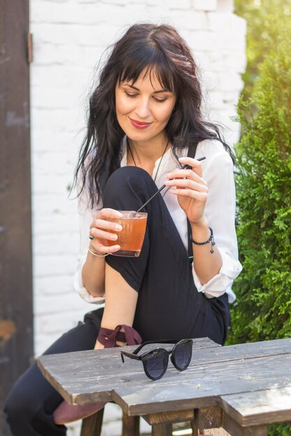 La mujer joven atractiva está bebiendo un cóctel en un café.