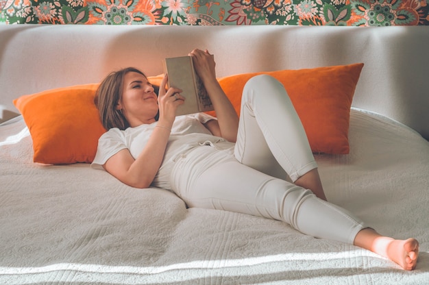 Mujer joven atractiva está leyendo un libro en casa