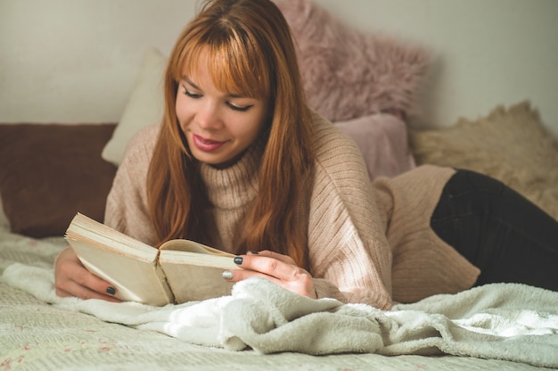 Mujer joven atractiva está leyendo un libro en casa