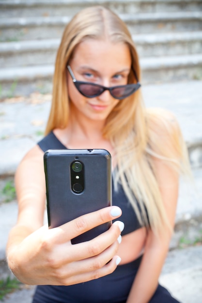 Mujer joven atractiva en gafas de sol tomando selfie.