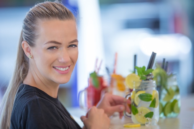 Mujer joven atractiva con una hermosa sonrisa mientras trabajaba en un bar preparando limonadas.