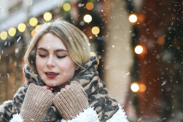 Mujer joven atractiva lleva bufanda caliente caminando en la ciudad durante las nevadas. Espacio vacio