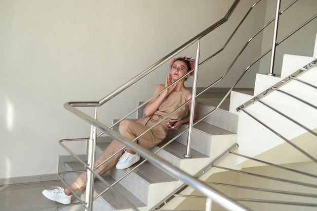 Mujer joven atractiva con maquillaje y peinado posando sentada en las escaleras