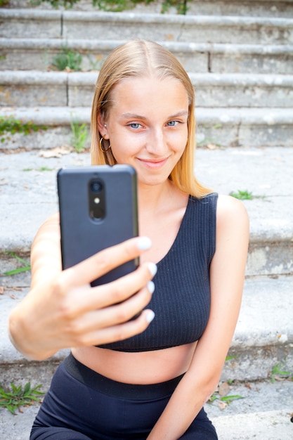 Mujer joven atractiva en negro tomando selfie.