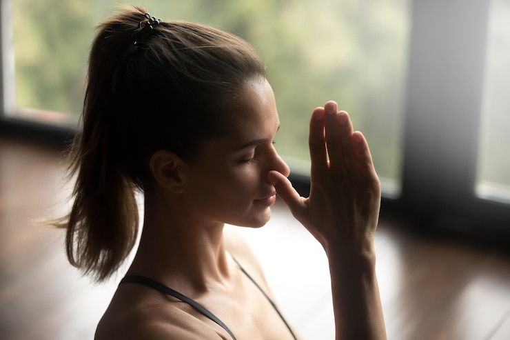 Foto mujer joven y atractiva practicando yoga haciendo ejercicio de respiración nasal alternativo nadi shodhana pranayama postura trabajando en el interior de cerca en el estudio de yoga vista lateral concepto de vida saludable consciente