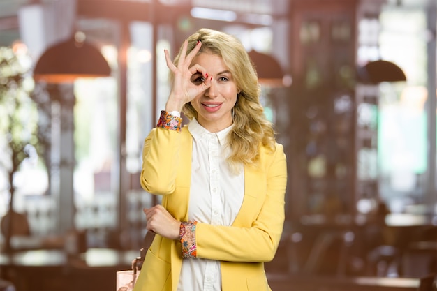 Mujer joven atractiva que gesticula bien. Bella dama de negocios en chaqueta amarilla y camisa blanca gesticulando bien.