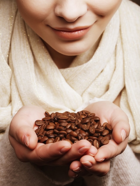 Mujer joven atractiva que sostiene los granos de café.