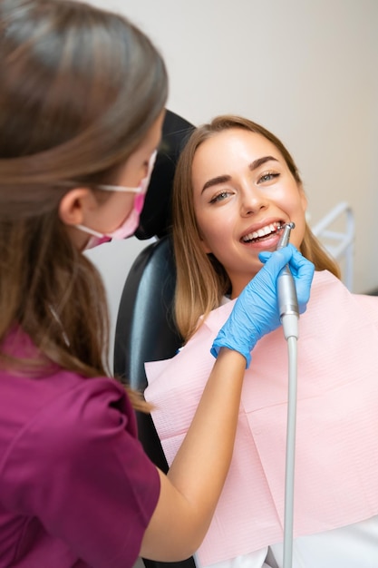 Mujer joven atractiva que tiene un cepillado profesional de dientes en la clínica de estomatología