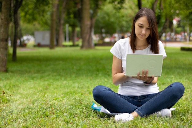 Mujer joven atractiva que usa la computadora portátil afuera