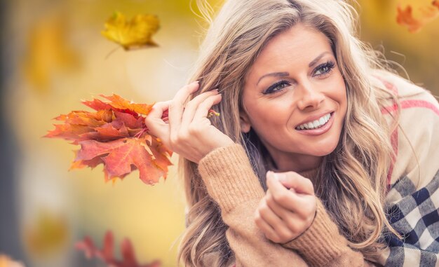 Foto mujer joven atractiva con sonrisa sensual se encuentra en el parque otoño.