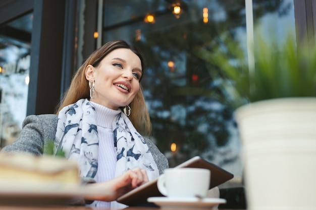 Mujer joven atractiva con tableta en café.