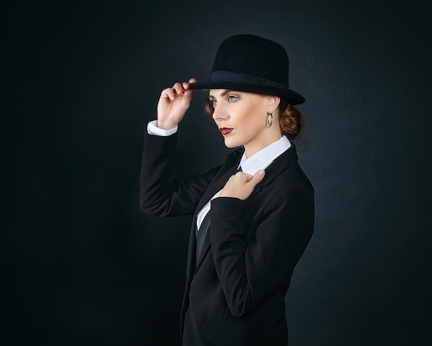 Mujer joven atractiva con un traje de hombre y un sombrero de fieltro. sesión de fotos de estilo retro