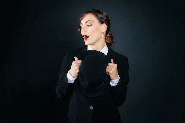 Mujer joven atractiva con un traje de hombre y un sombrero de fieltro. sesión de fotos de estilo retro