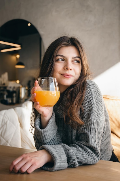 Foto mujer joven atractiva con un vaso de jugo de naranja en el interior de un café