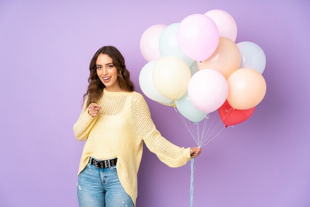 Mujer joven atrapando muchos globos en puntos dedo en ti