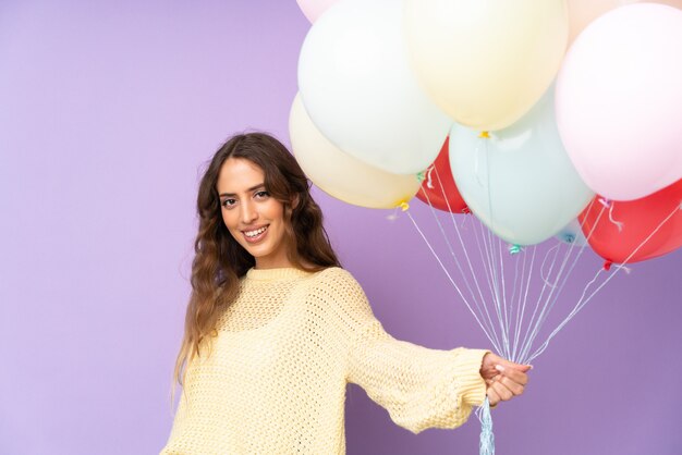 Mujer joven atrapando muchos globos en