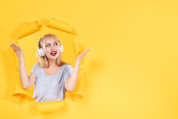 Mujer joven en auriculares con audio de música de sonido de fondo amarillo