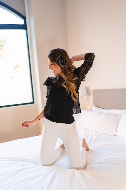 Mujer joven con auriculares disfrutando de la música encima de la cama