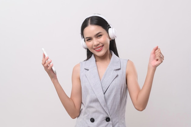 Una mujer joven con auriculares disfrutando de la música sobre fondo blanco.