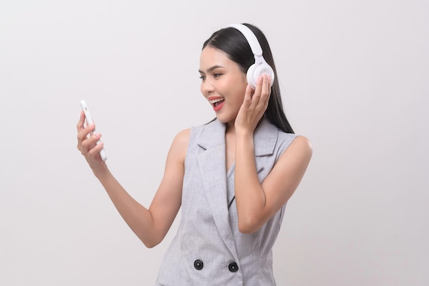 Una mujer joven con auriculares disfrutando de la música sobre fondo blanco.