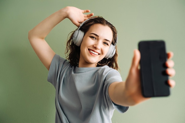 Una mujer joven con auriculares inalámbricos escuchando música bailando Energetic Beats Young Lady E