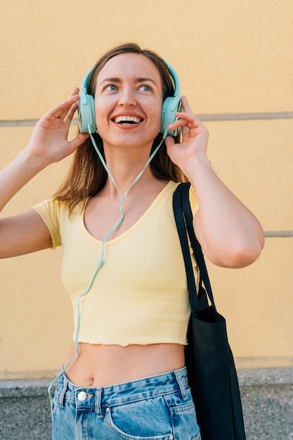 Mujer joven con auriculares de menta y gorra negra afuera en la calle