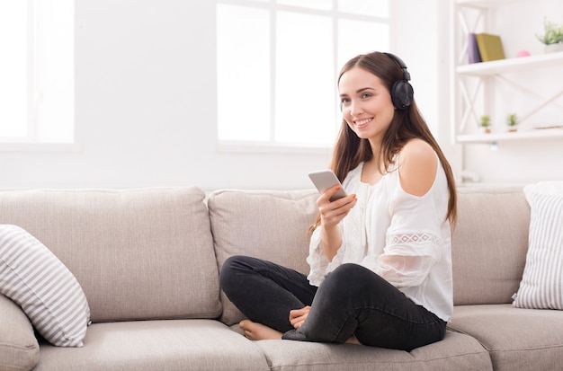 Mujer joven en auriculares con móvil