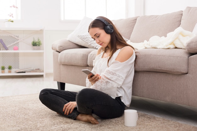 Mujer joven, en, auriculares, en el piso