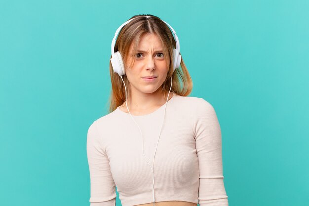 Mujer joven con auriculares sintiéndose desconcertado y confundido