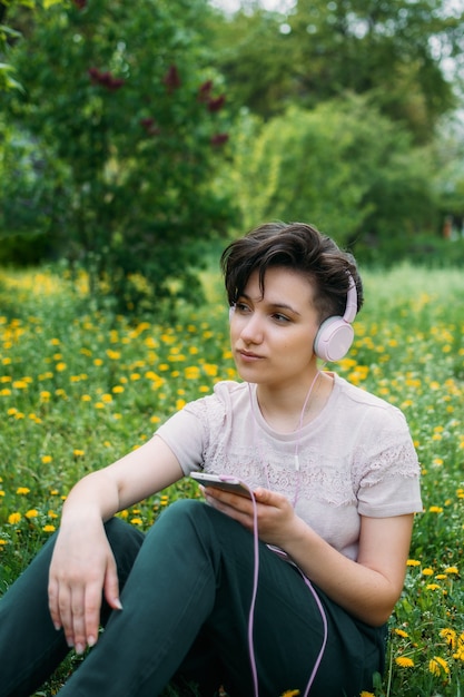 Mujer joven en auriculares y con smartphone usando la aplicación de redes sociales de chat de audio escuchando voz