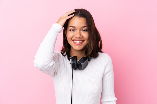 Mujer joven con auriculares sobre pared rosa aislado con sorpresa y expresión facial conmocionada