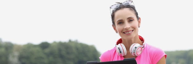 Mujer joven con auriculares con tableta al aire libre trabajo remoto y concepto de trabajo independiente