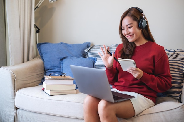 Una mujer joven con auriculares usando una computadora portátil para el estudio en línea en casa