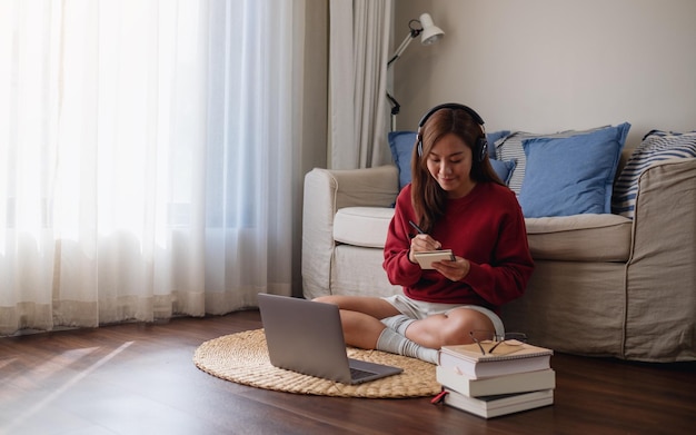Una mujer joven con auriculares usando una computadora portátil para el estudio en línea en casa