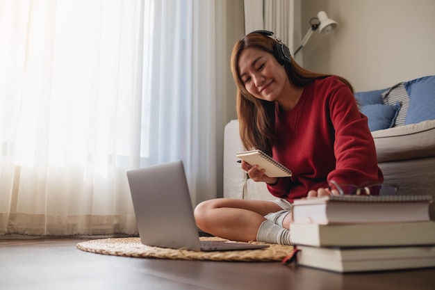 Una mujer joven con auriculares usando una computadora portátil para el estudio en línea en casa