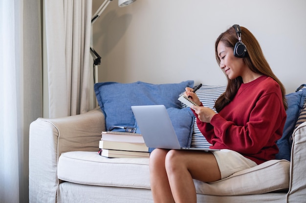 Una mujer joven con auriculares usando una computadora portátil para el estudio en línea en casa