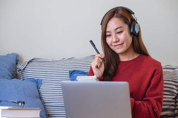 Una mujer joven con auriculares usando una computadora portátil para el estudio en línea en casa