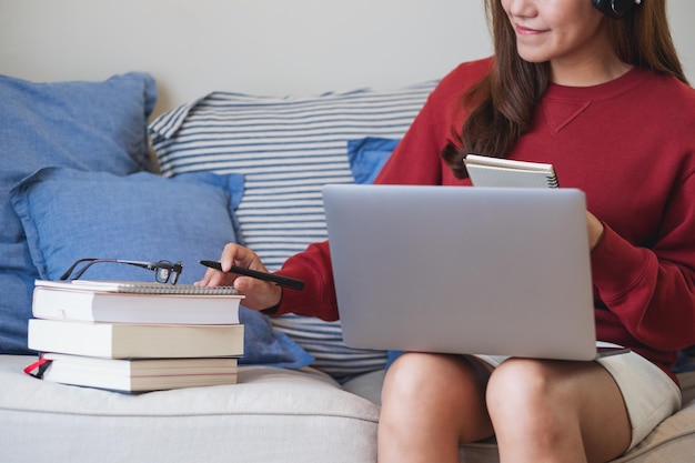 Una mujer joven con auriculares usando una computadora portátil para el estudio en línea en casa