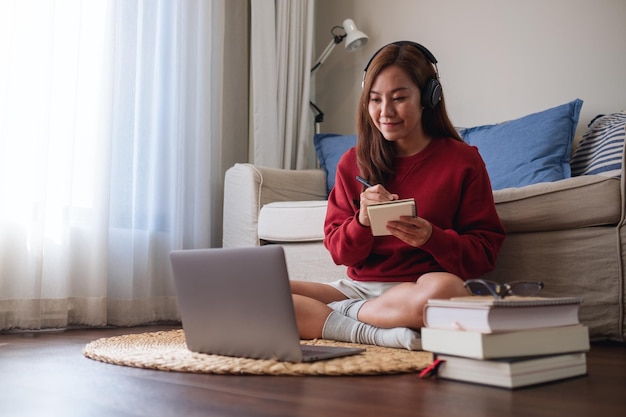 Una mujer joven con auriculares usando una computadora portátil para el estudio en línea en casa