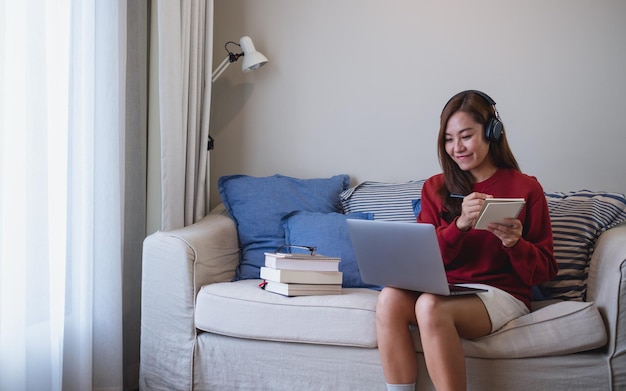 Una mujer joven con auriculares usando una computadora portátil para el estudio en línea en casa