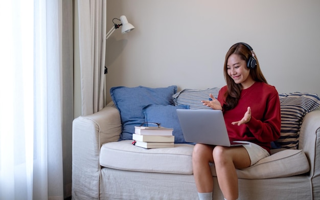Una mujer joven con auriculares usando una computadora portátil para el estudio en línea en casa