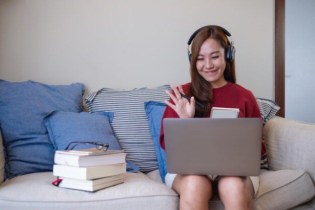 Una mujer joven con auriculares usando una computadora portátil para el estudio en línea en casa