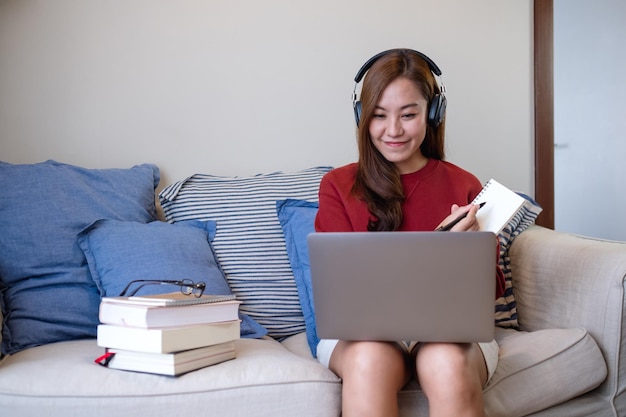 Una mujer joven con auriculares usando una computadora portátil para el estudio en línea en casa