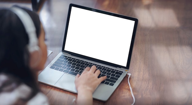 Mujer joven con auriculares usando laptop mientras está acostado en el piso en casa.