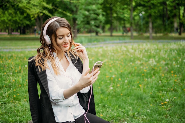 Mujer joven con auriculares usando el teléfono mientras está de pie en la hierba