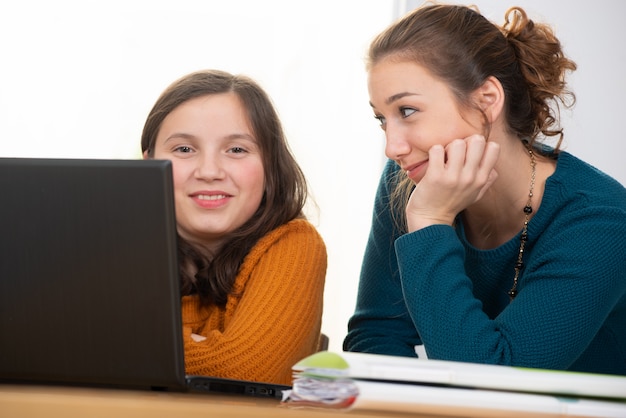 Mujer joven ayuda a una muchacha adolescente con la tarea