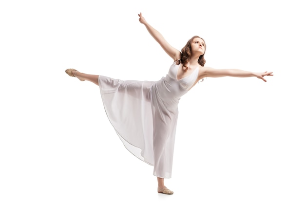 Mujer joven bailando en un hermoso vestido blanco sobre blanco